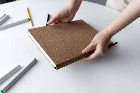 Hands organizing sketchbook on a white table