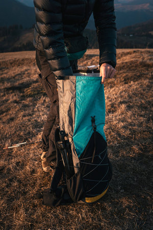 Hiker Packing Gear into Backpack at Dusk