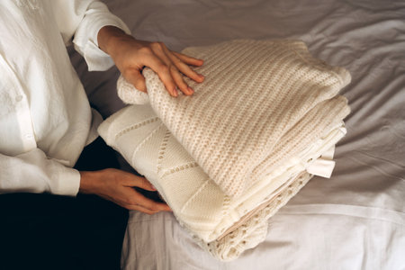 A Woman Organizing Cozy Knitwear and Neutral Clothingの写真素材