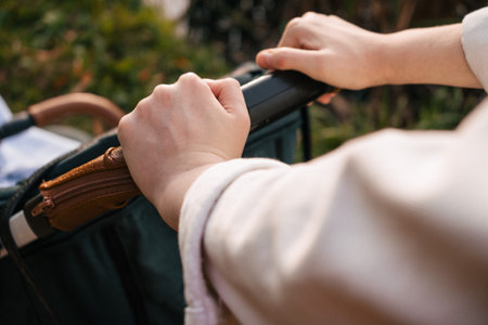 Close-Up of Hands Pushing Stroller Handle Outdoors in Daylight
