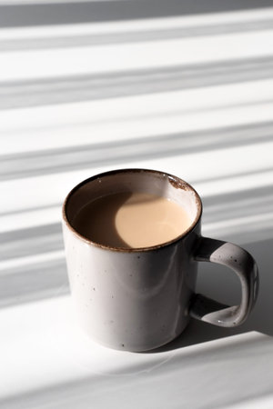 Top View of Ceramic Mug of Coffee or Tea Casting a Strong Shadow on White Surfacev