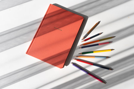 Creative Workspace with Notebook and Colorful Pencils in Natural Lightの写真素材