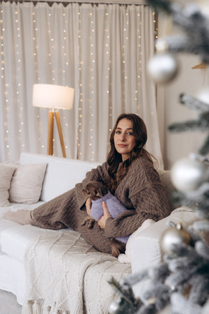 Woman Enjoying Cozy Moments with Her Chihuahua Dog in a Festive Christmas Settingの写真素材