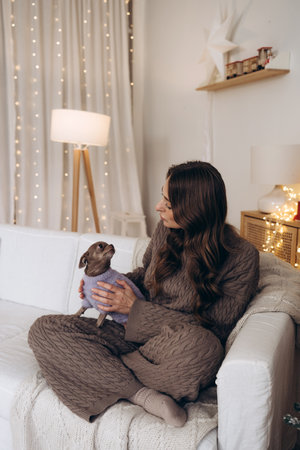 Woman Enjoying Cozy Moments with Her Chihuahua Dog in a Festive Christmas Settingの写真素材