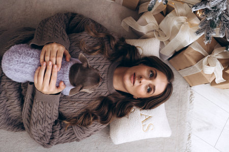 Woman relaxing with small dog on cozy Christmas morning indoorsの写真素材