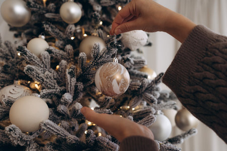 Close-up of a hand decorating a Christmas tree with ornamentsの写真素材