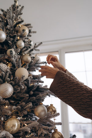 Close-up of a hand decorating a Christmas tree with ornamentsの写真素材
