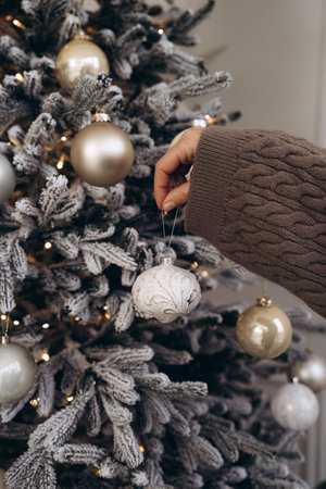 Close-up of a hand decorating a Christmas tree with ornamentsの写真素材