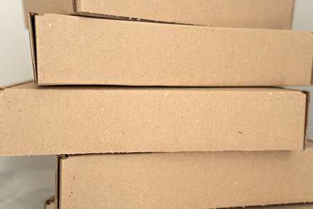 Detailed close-up of stacked kraft cardboard boxes against a neutral background. Ideal for eco-friendly packaging, gift wrapping, shipping, and storage solutions.の写真素材