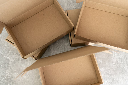 Three open kraft cardboard boxes on a concrete surfaceの写真素材