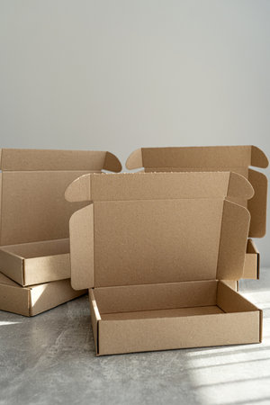 Three kraft cardboard boxes with open lids on a concrete tableの写真素材