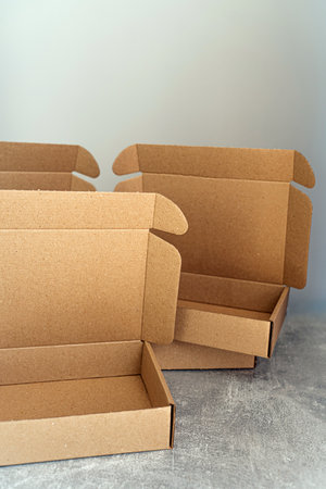 Three open kraft cardboard boxes on a concrete surfaceの写真素材