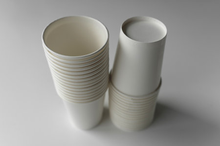 Minimalistic image of white paper cup stacks. Eco-conscious design for sustainable living, coffee shops, events, or branding mockups.の写真素材