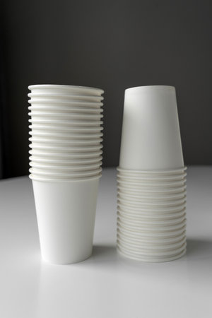 Minimalistic image of white paper cup stacks. Eco-conscious design for sustainable living, coffee shops, events, or branding mockups.の写真素材