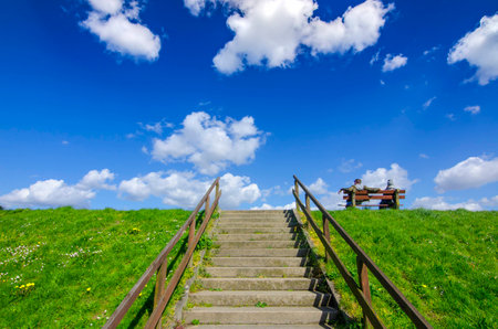 People on a bench and stone steps against a cloudy sky backgroundの写真素材