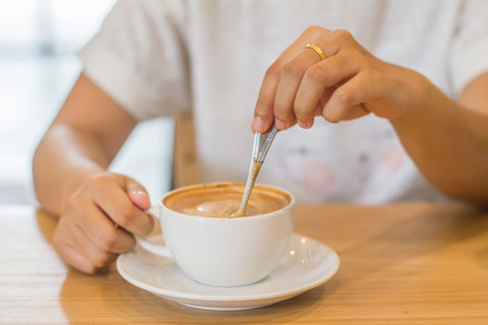 Closeup of hands with coffee cups in a cafeの写真素材