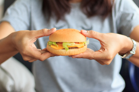 Close-up fast food burger, burger in the young woman hand, holding in woman hands fast food burger, の写真素材