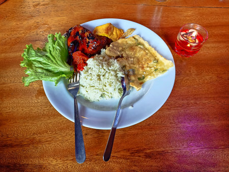 Rice with chicken and vegetables in a plate on a wooden tableの写真素材