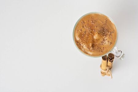 Dalgona Coffee Iced, a Korean fashionable whipped black instant coffee with milk and chocolate chips, on a white background. cinnamon sticks touch a glass. Copy space. top view.の写真素材