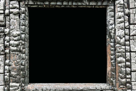 The charred window frame of a burnt wooden apartment building after a fire.の写真素材
