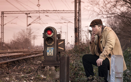 A young man sitting next to the railroad.の写真素材