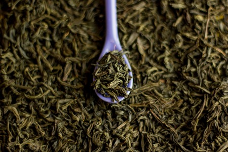 Black tea in a purple spoon on a black tea background. Close-up.の写真素材