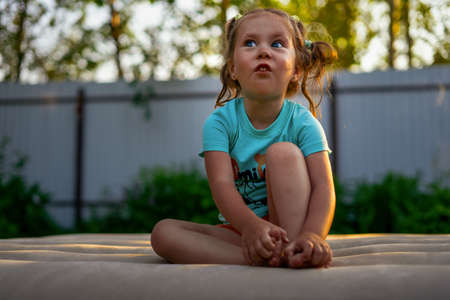 little girl makes faces on inflatable mattress outsideの写真素材
