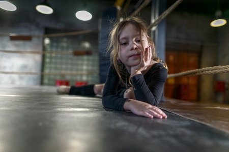 Little gymnast is working out in the gym in a black swimsuit