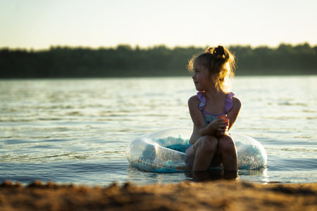 Little girl on the beach sits in the water on an inflatable ringの写真素材