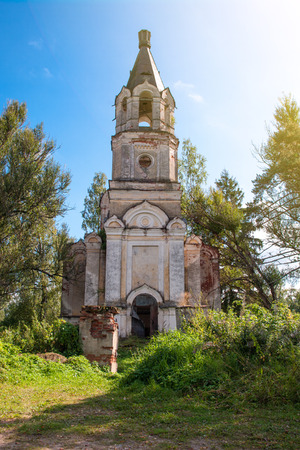 The ruins of old Christian Church on a background of bright trees and a blue sky.の写真素材