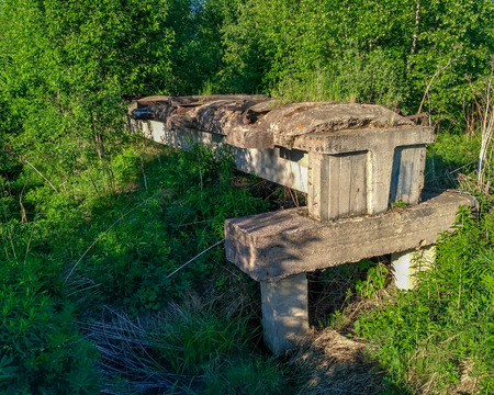 old unfinished destroyed narrow-gauge railway on concrete blocks passing through a forest swamp close-up.の写真素材
