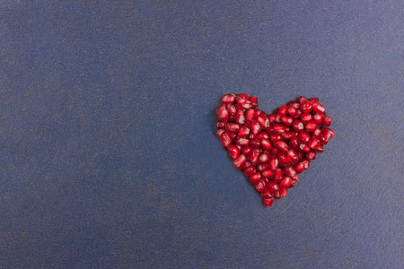 Post Card with Heart of fresh pomegranate on background of painted stone Closeup. Romantic Valentines day concept.の写真素材