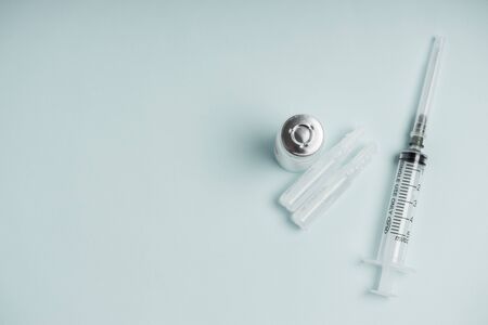 Medicine bottle with vaccine and disposable syringe closeup on blue background. Health pharmacy pharmacology concept with space for text.の写真素材
