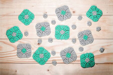 Lot of knitted gray-green, square napkins on the background of light wooden table. Crochet. Elements of needlework.の写真素材