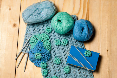 Composition of knitting tools and crocheted blue-green openwork napkins, balls of colored yarn,...