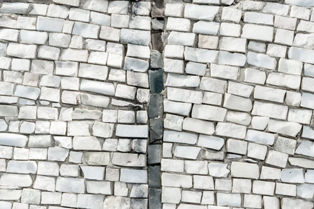 surface of old crumbling abstract decorative mosaic. White ceramic stones on wall are divided into...
