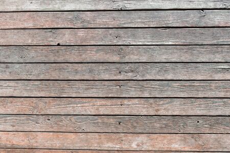 Close-up of wooden texture of wall boards driven in with rusty nails, weathered planks with deep cracks and worn brown paint. Abstract rustic background for design, blank template.の写真素材