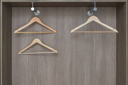 Fragment of modern wardrobe from inside. Empty wooden clothes hangers hang on a metal rail. Accessories made of environmental material.の写真素材