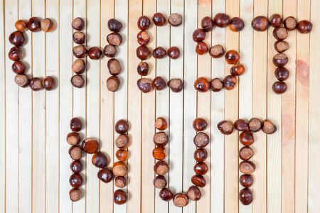 Word chestnut is laid out with ripe brown nuts chestnuts on light wooden background close up for your design. Flat lay.の写真素材