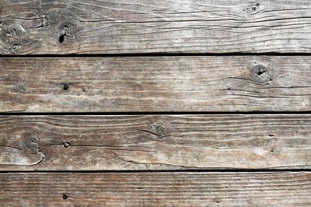 Texture of wooden weathered planks with deep cracks with rusty nails driven in of rural house wall. Natural background for your design, blank template.の写真素材