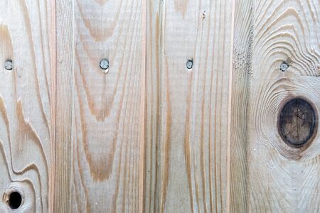 Texture of light wooden planks with large dark cracked knots and nails driven into them, surface with natural pattern. Abstract, vertical background. Template for your design.の写真素材