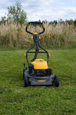 Yellow lawn mower on the green field.の写真素材