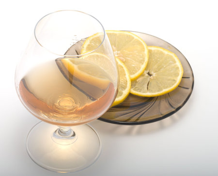 Brandy in a glass and the cut lemon on a saucer.の写真素材