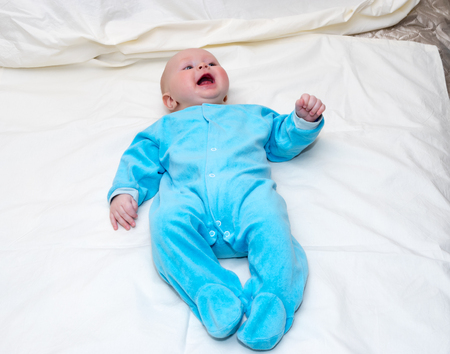 Four month old baby smiling while lying on the bedの写真素材