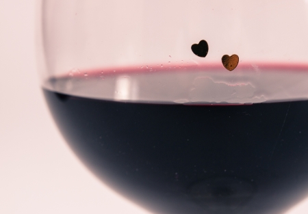 Two hearts on a glass with red wineの写真素材