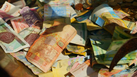 Banknotes thrown into the museum's moneybox, a drop in money from many countries of the world to rebuild monuments. Krakow, Malopolskie, Poland - 03/05/2015のeditorial素材