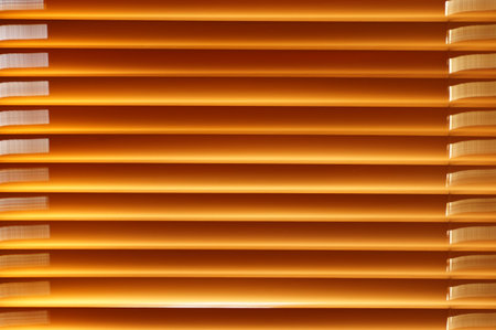 Abstract background - wooden blinds on the window, large brown-golden horizontal stripes lit by the...