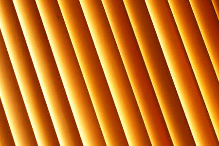 Abstract background - wooden blinds on the window, large brown and gold horizontal stripes lit by the sunの写真素材