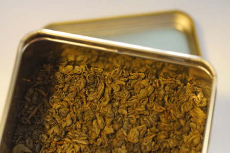 Dried green tea leaves. Preparing a hot drink. Several servings of tea in a zoomed-in view. Tea in a metal tin.の写真素材