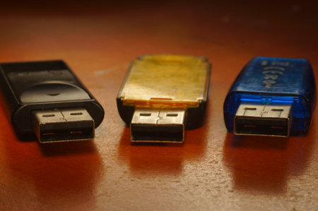 USB flash drive - black, yellow and blue, on a red background. Three used computer flash drives,...